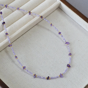 Elegant amethyst beaded necklace with gold spacers on a beige velvet jewelry tray