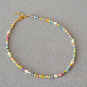 Detail of colorful polymer clay beaded necklace with freshwater pearls and gold clasp