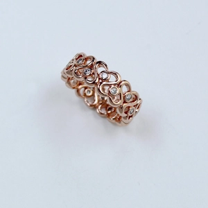 Détail d'une bague filigrane en or rose avec motifs en S et zircons ronds incrustés