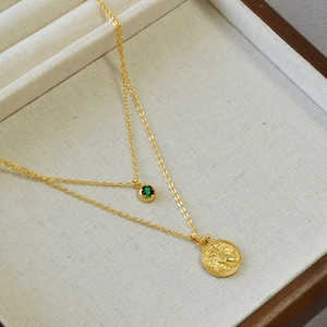 Detail of double-layer brass gold necklace with malachite stone and Egyptian coin pendant