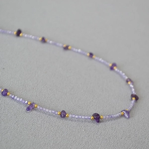 Macro shot of elegant purple amethyst beaded necklace with polished gold metal spacer beads