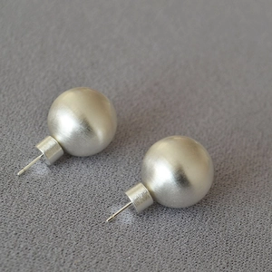 Vue détaillée de boucles d'oreilles boules avec une texture en argent mat brossé