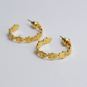Detailed close-up of gold-plated Hamsa hand hoop earrings with white zircon settings