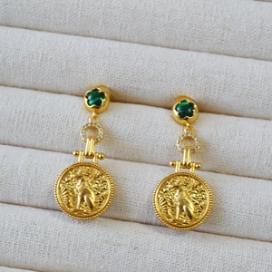 Detail of vintage brass earring with green malachite petal and ancient coin cat relief