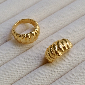 Détail de la bague croissant dorée avec texture en spirale sur un plateau en velours