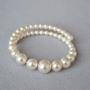 Detail of double-layer gradient pearl bracelet with cream pearls on textured fabric