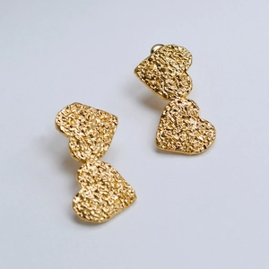 Detail of gold double heart earrings with hand-hammered texture and rustic finish