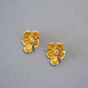 Macro shot of 3D floral earrings in brushed gold finish with a sparkling center zircon