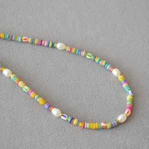 Close-up of bohemian beaded necklace with colorful clay discs and baroque pearls
