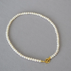 Detail view of natural white freshwater pearls necklace with golden toggle clasp closure