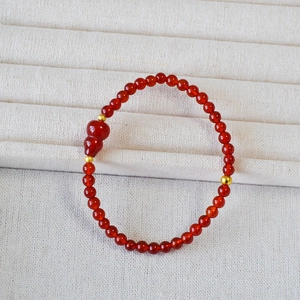 Dettaglio del bracciale con perline di agata rossa, pendente a zucca e sfere dorate