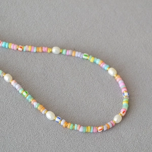 Detailed view of bohemian colorful beaded necklace with white pearls and gold accents