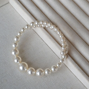 Macro view of gradient pearl bracelet with cream white pearls in a beige jewelry box