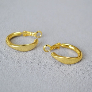 Macro shot of twisted irregular gold hoop earrings with polished metallic texture