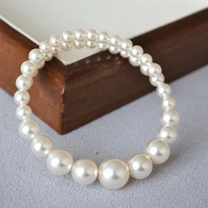 Elegant gradient pearl bracelet with cream white beads on a premium gray fabric background