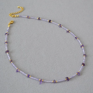 Detail view of irregular amethyst beads and golden metal spacers on beaded necklace
