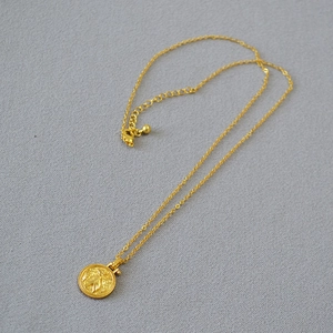 Detailed view of vintage gold-plated brass coin necklace with lobster clasp and extension
