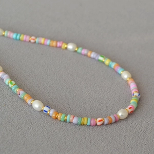 Close-up of colorful beads and white pearls necklace with golden metal spacers