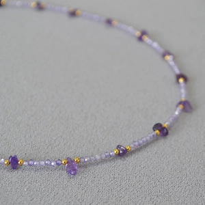 Macro shot of purple beaded necklace with irregular amethyst stones and gold spacers