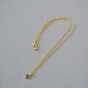 Detail view of gold-plated brass necklace with green malachite coin and lobster clasp