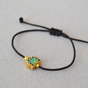 Macro view of brass lotus pendant with blue enamel on adjustable black woven cord