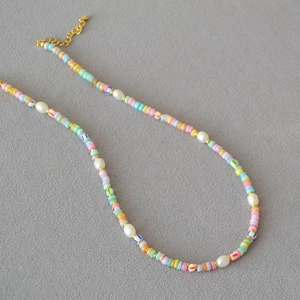 Macro detail of Bohemian colorful polymer clay beads with white baroque pearls and gold clasp