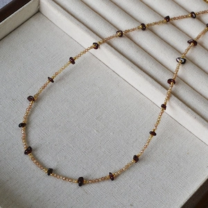 Macro detail of champagne faceted beads and red garnet stones on a luxury gold necklace
