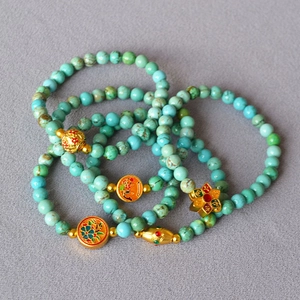 Macro detail of turquoise beaded bracelets with vintage brass and cloisonne enamel charms