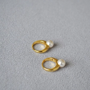 Détail des boucles d'oreilles créoles en laiton doré avec perles rondes blanches