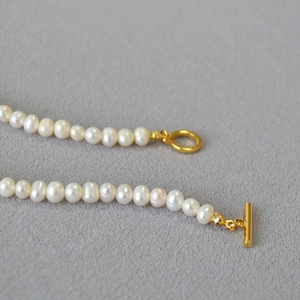 Detailed macro view of natural baroque pearls featuring a decorative golden OT clasp closure