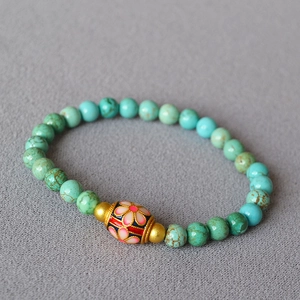 Macro detail of turquoise beaded bracelet with floral cloisonne bead and brass spacers