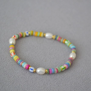 Detail of colorful Bohemian beaded necklace with sea shells and pearls on a textured fabric
