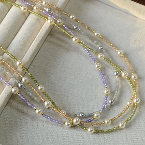Detail of layered beaded necklace with pearls, colored gemstones and gold spacer beads