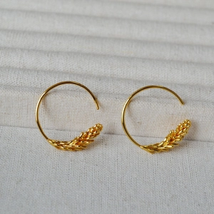 Detailed view of gold plated brass wheat ear earrings with geometric circular design