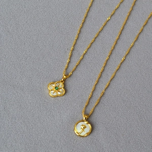 Détail de colliers avec pendentifs trèfle et rose dorés avec incrustation de nacre