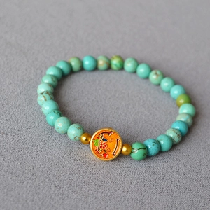 Macro view of a turquoise beaded bracelet with gold flower enamel pendant details