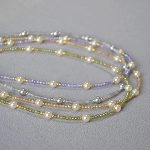 Detailed close-up of colorful gemstone bead necklaces with white pearls and gold accents