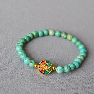 Detailed macro view of vintage turquoise beaded bracelet with golden enamel lotus charm