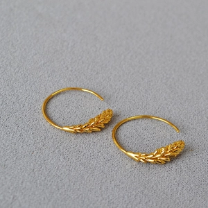 Macro shot of gold-plated brass hoop earrings with realistic wheat grain texture