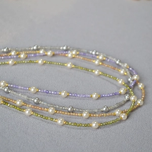 Detail of beaded necklace with white pearls, faceted crystals and gold spacer beads