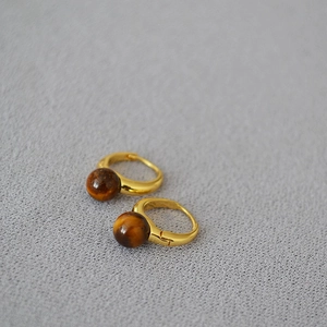 Vue macro de boucles d'oreilles en laiton doré avec perles en pierre œil de tigre