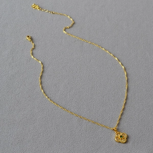 Vue macro détaillée du pendentif trèfle doré avec une pierre précieuse verte centrale