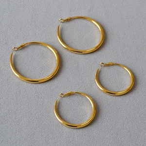 Minimalist high-polish gold hoop earrings in two sizes on grey fabric background
