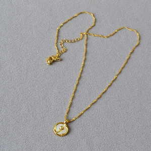 Détail d'un pendentif rose dorée avec nacre sur une chaîne maille torsadée fine