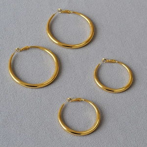 Macro shot of two pairs of polished gold oversized hoop earrings on a textured background