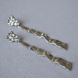 Macro detail of silver-plated wavy earrings with minimalist wrinkled metal texture