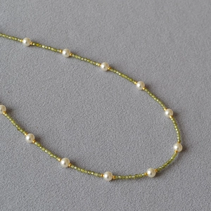 Close-up of fresh green beaded necklace with white pearls and gold metal spacers