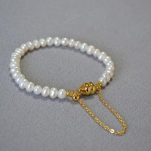 Détail de perles baroques blanches avec fermoir magnétique doré et chaînette de sécurité