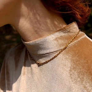 Vintage gold-plated beaded necklace with delicate rice beads worn over brown velvet
