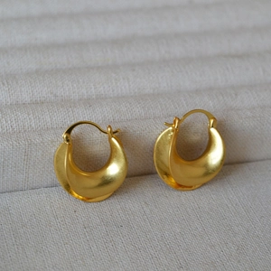 Macro detail of French retro matte gold-plated brass C-shaped geometric earrings